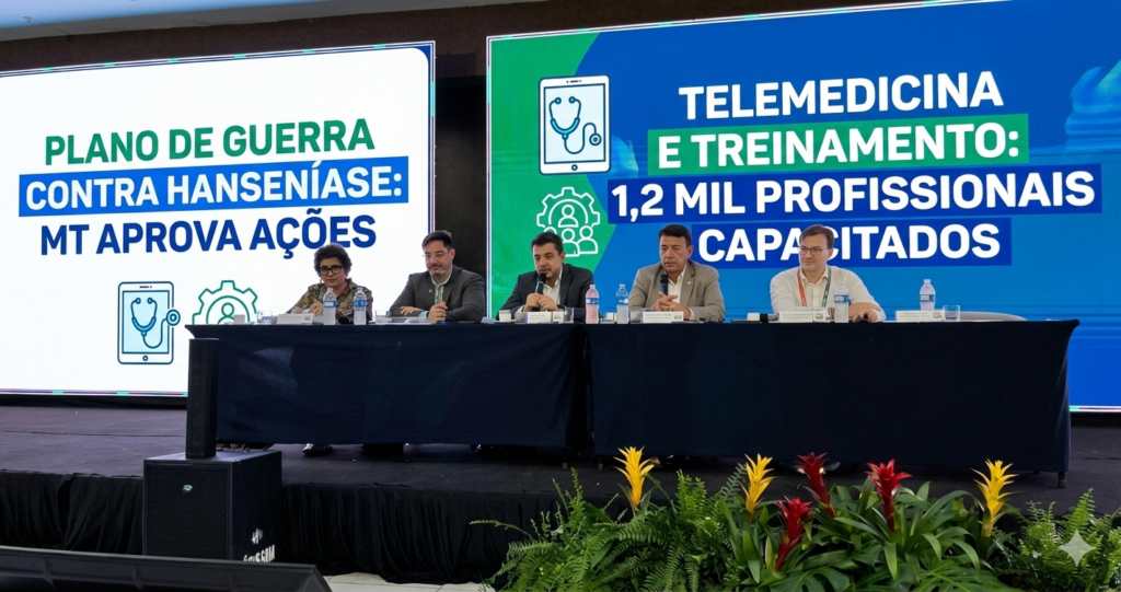 Uma autoridade de saúde discursa em uma coletiva de imprensa sobre o 'Plano de Guerra contra Hanseníase' em Mato Grosso. Ao fundo, telões LED exibem mensagens claras: 'MT aprova ações' e 'Telemedicina e treinamento: 1,2 mil profissionais capacitados', com ícones de saúde digital. A imagem tem alta clareza e autoridade, no estilo de fotojornalismo para portal de notícias, adequada para visualização em dispositivos móveis.